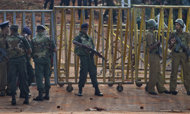 Army soldiers and police officers stand guard at the entrance of a prison in Colombo, Sri Lanka, Saturday, Nov. 10, 2012. A shootout between rioting prisoners and security forces at the prison killed 27 inmates, while police said Saturday that they arrested five prisoners who had managed to escape. (AP Photo/Gemunu Amarasinghe)